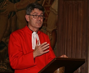 Le révérend Andrew Tremlett, chanoine de Westminster et recteur de St. Margaret’s, accueillant les participants à la réunion commémorative à l’abbaye de Westminster, le 27 mai 2014 ; réunion qui a marqué le sixième anniversaire de l’emprisonnement de sept anciens responsables bahá’ís d’Iran.