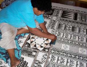Bale Jione peint le motif sur le tissu en écorce en utilisant les pochoirs qu’elle et ses collaboratrices ont fabriqués.