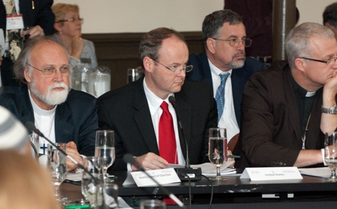 Au centre, Kenneth E. Bowers, secrétaire de l'Assemblée spirituelle nationale des bahá’ís des États-Unis, un des représentants bahá’ís au Sommet des Religions mondiales, premier Sommet interreligieux en relation avec le G8 auquel les bahá’ís ont été invités.
