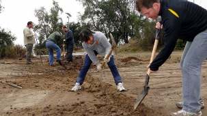 De jeunes travailleurs à Santiago, au Chili, préparant le sol pour la pose d’une clôture de sécurité autour d’un local de bureaux temporaire et d’une zone de stockage destinés à la maison d’adoration bahá'íe en cours de construction.