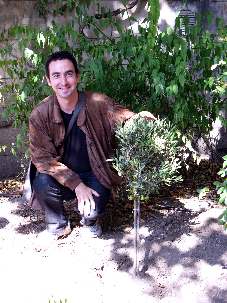 Joël, un des participants, heureux de poser à côté de l'olivier, symbole de paix, planté à cette occasion dans le jardin du Forum 104.
