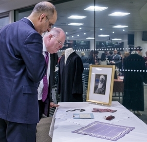 Le député Eric Pickles, secrétaire d’État aux Communautés et au Gouvernement local – sur la droite – examinant des objets personnels et historiques associés à ‘Abdu’l-Bahá, au cours d’une réception organisée par le gouvernement britannique pour la communauté bahá’íe, le 28 novembre 2012.