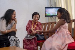 Une jeune fille présente une collection d’écrits sacrés qu’elle a rassemblés dans un livret. Datuk Lok Yim Pheng (au centre), commissaire de la Commission des droits de l’homme de Malaisie, et Omna Sreeni-Ong (gauche), membre de la communauté bahá’íe, écoutent attentivement.