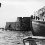 Bahá’u’lláh est entré dans Acre le 31 août 1868 par la porte de la mer, visible à gauche le long de la digue. Cette photo, datant de 1920, montre à quoi ressemblait la porte de la mer à l’arrivée de Bahá’u’lláh, avec l’eau léchant le pied du mur. Aujourd’hui, cette zone le long de l’ancienne digue est une promenade pavée.