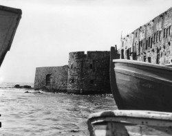 Bahá’u’lláh est entré dans Acre le 31 août 1868 par la porte de la mer, visible à gauche le long de la digue. Cette photo, datant de 1920, montre à quoi ressemblait la porte de la mer à l’arrivée de Bahá’u’lláh, avec l’eau léchant le pied du mur. Aujourd’hui, cette zone le long de l’ancienne digue est une promenade pavée.
