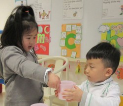 La notion de service est intégrée au programme de l’école des Nations. Ici, une élève de maternelle offre de l’eau à son camarade de classe lors d’une leçon.