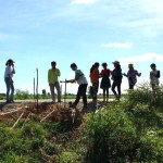 Photographie prise avant la crise sanitaire actuelle. Les efforts de jeunes adolescents pour planter des arbres afin d’améliorer la qualité de l’air et d’abriter de la chaleur ont eu l’avantage supplémentaire d’empêcher l’érosion d’une partie de route en cas d’inondations