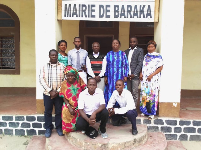 Rassemblement de personnes organisé conformément aux mesures de sécurité exigées par le gouvernement. Des membres de l’Assemblée spirituelle locale bahá’íe rendent visite à la maire adjointe de Baraka, Emerite Tabisha (debout, troisième en partant de la droite).