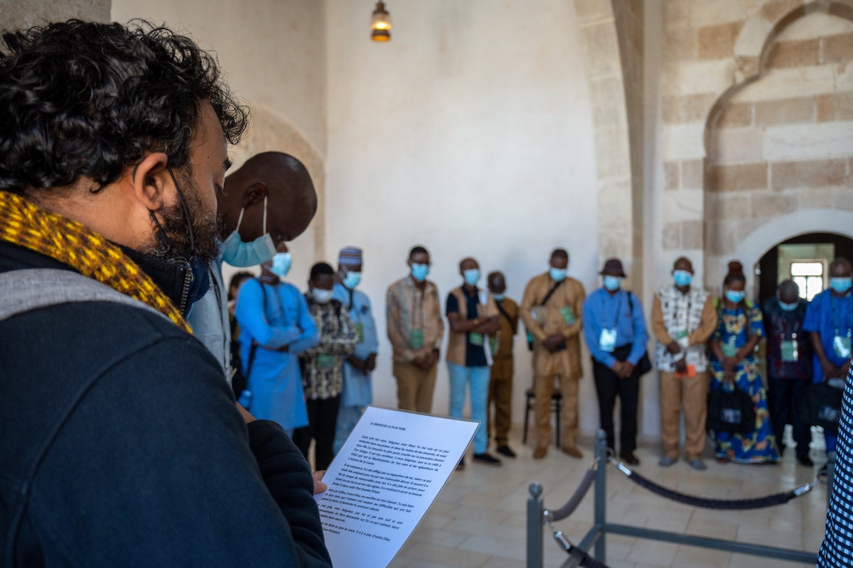 Délégué lisant un passage des écrits bahá’ís lors de la visite de la cellule de la prison.