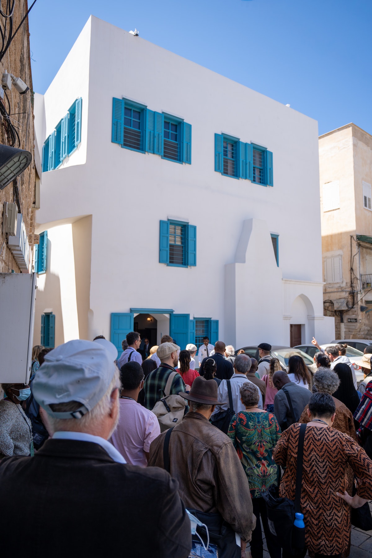 Les délégués se rassemblent derrière la maison de ‘Abbúd avant leur visite. Les fenêtres de l’étage supérieur, à gauche, sont celles de la pièce où Bahá’u’lláh a révélé son Plus-Saint-Livre.
