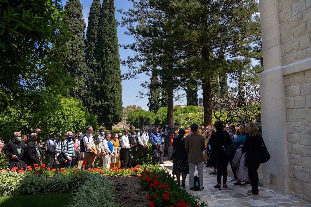 Un groupe de participants à la Convention de différents nationalités écoute un guide dans les jardins de la maison de ‘Abdu’l-Bahá.