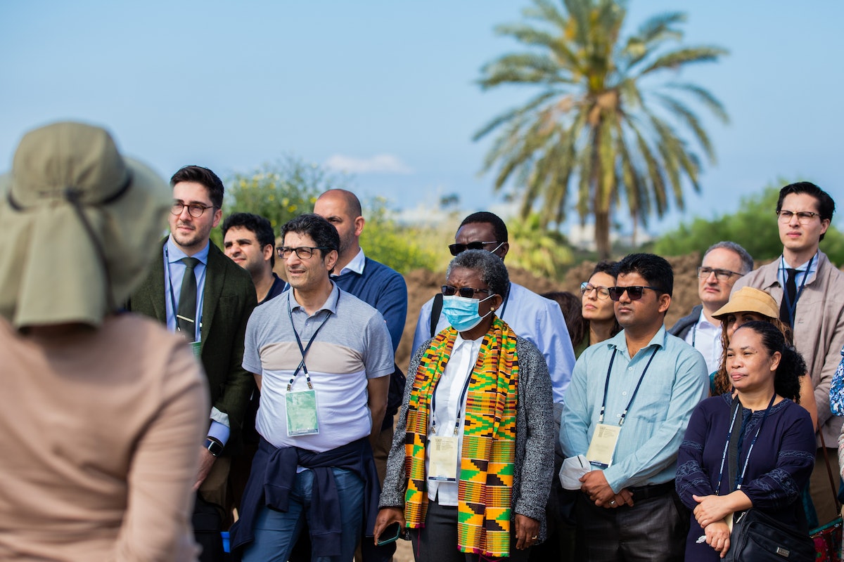 Des délégués et d’autres invités écoutant une présentation sur le site du futur mausolée de ‘Abdu’l-Bahá.