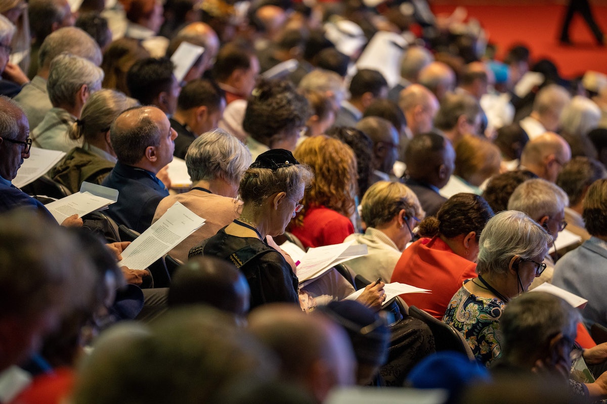 Les délégués à la 13e Convention internationale bahá’íe lisent le message du Riḍván de la Maison universelle de justice