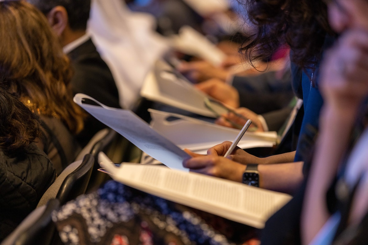 Une déléguée prend des notes pendant que le message du Riḍván de la Maison universelle de justice est lu à haute voix pendant la session du matin.