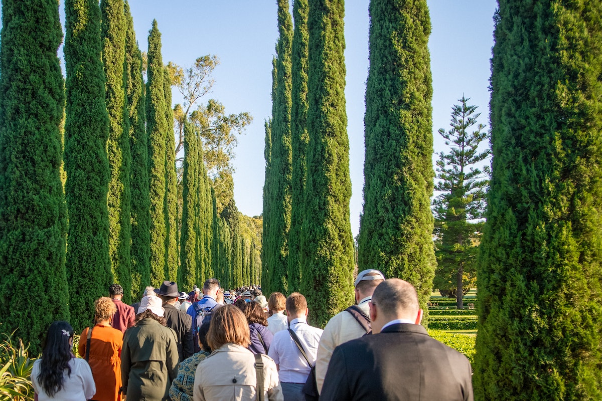 Les participants à la Convention marchent entre des rangées de cyprès alors qu’ils effectuent la circumambulation du tombeau de Bahá’u’lláh.