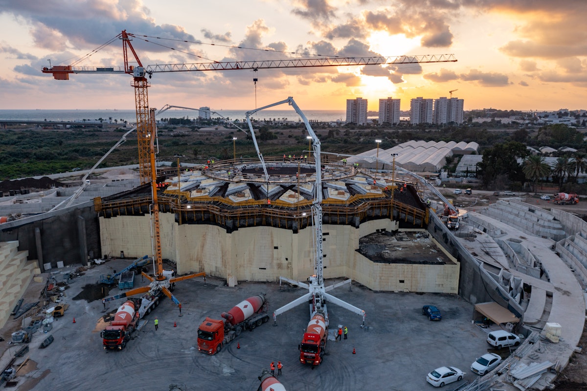 Le soleil se couche dimanche soir et les travaux de coulée de la structure du toit sont en cours. La base de la berme est sert d’aire de transit pour deux des pompes à béton.